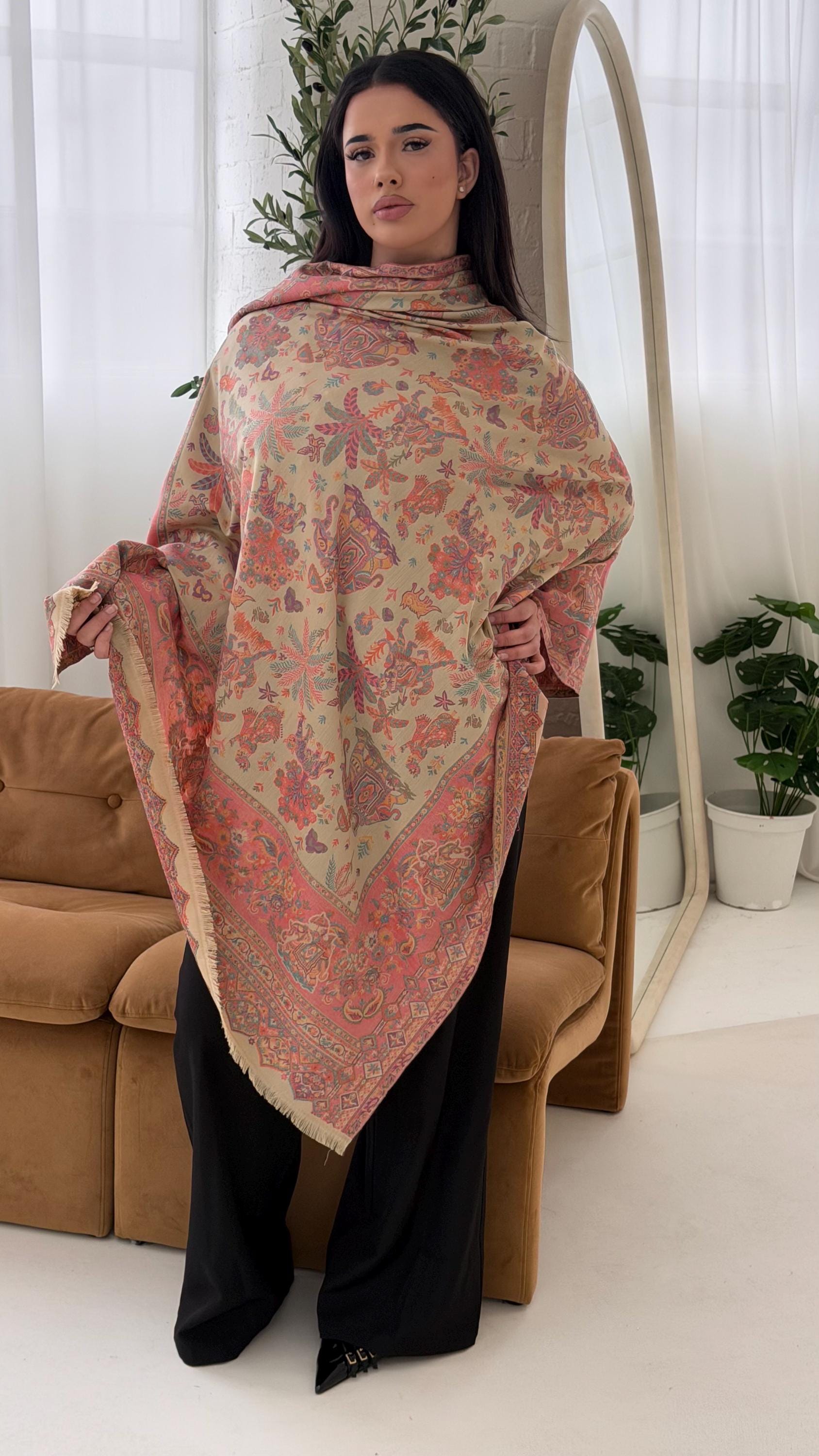 Woman holding a beige patterned pashmina shawl  in a living room setting