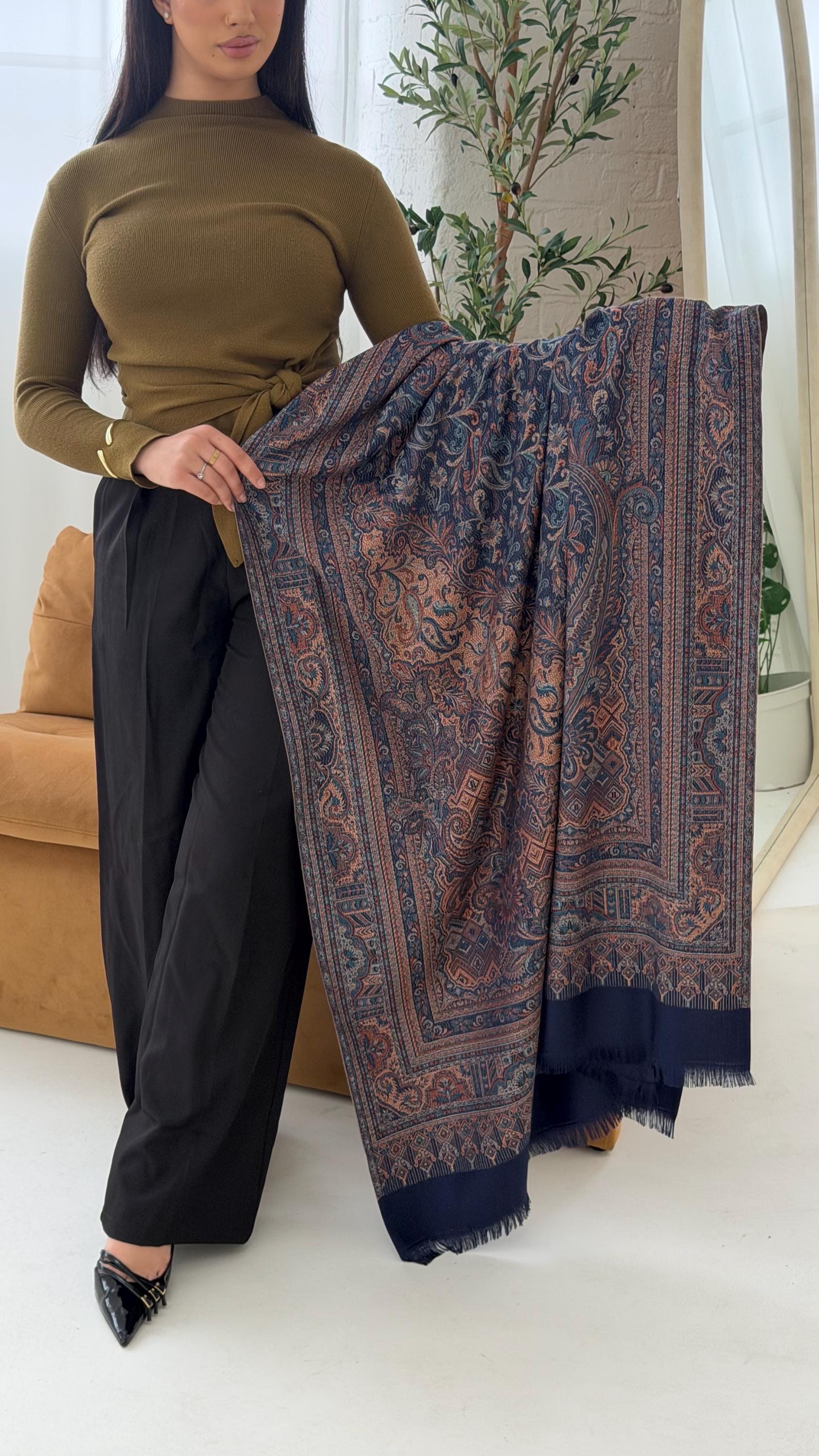 Woman holding a blue scarf in a room with a couch and plant.