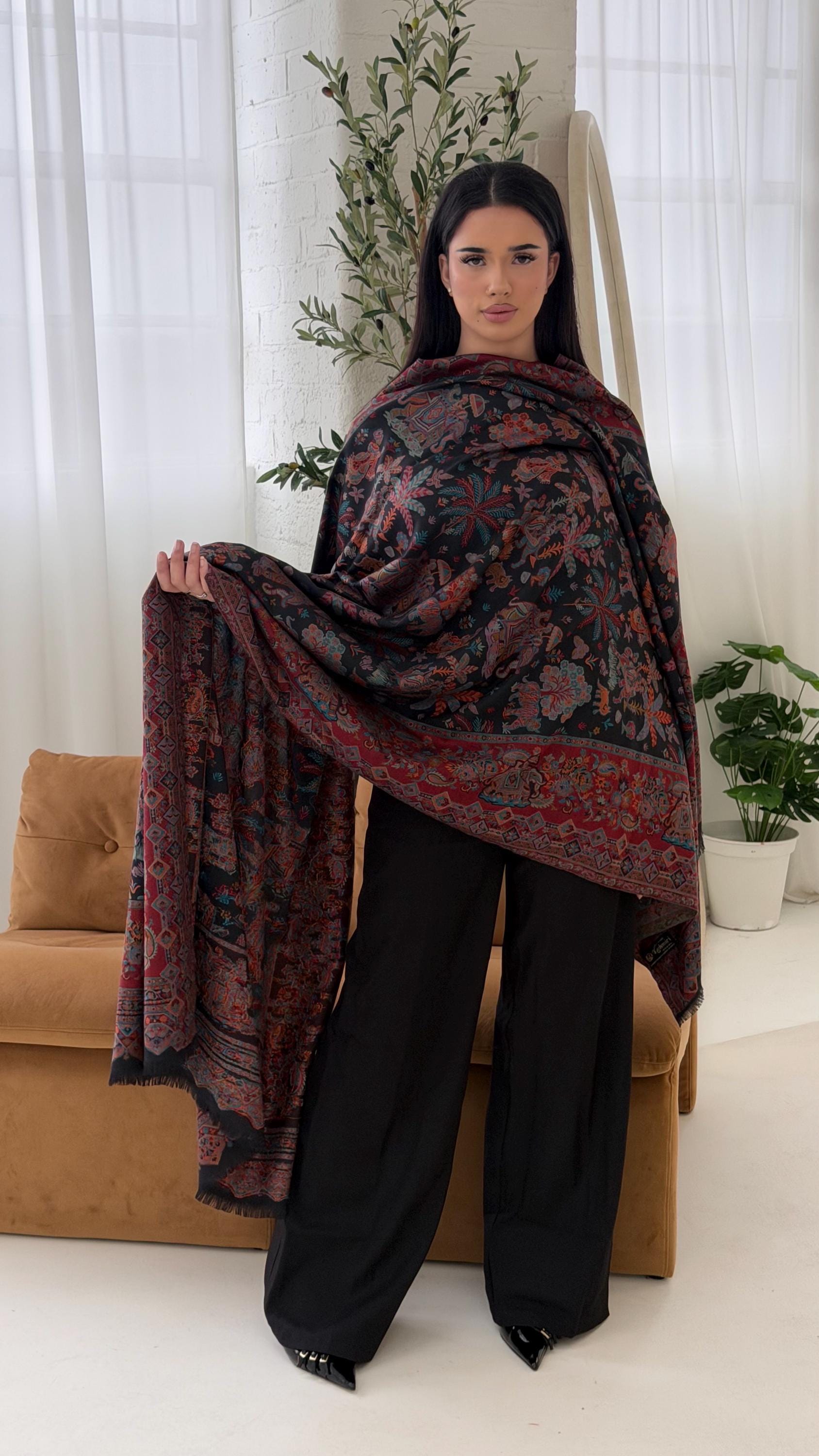 Woman holding a black patterned pashmina shawl scarf in a living room setting