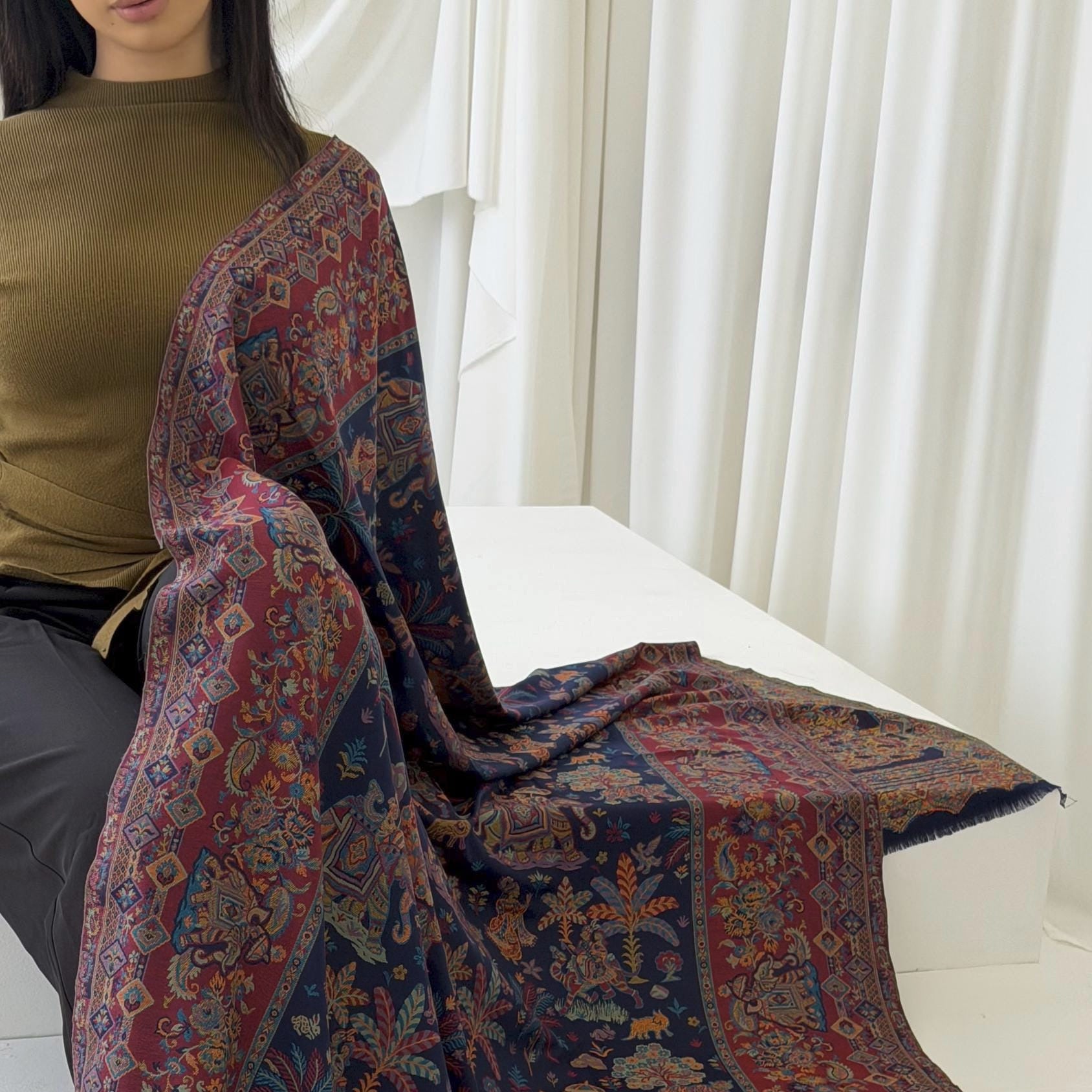 Person wearing a blue patterned pashmina shawl scarf  with a white background