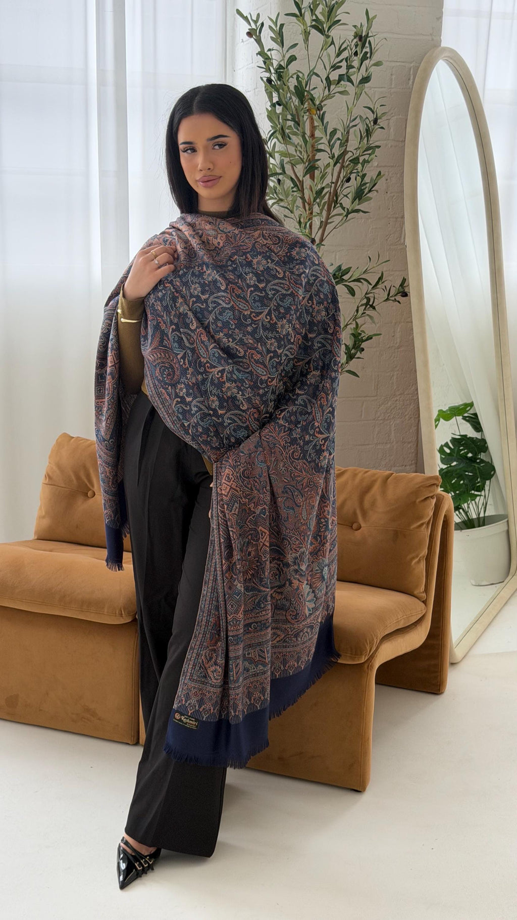 Woman holding a blue pashmina shawl scarf in a living room setting