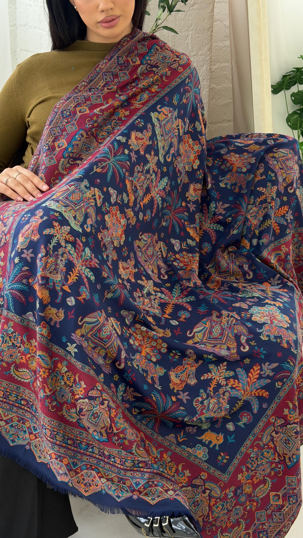 Woman holding a blue patterned pashmina shawl scarf, colorful patterned scarf with intricate designs.