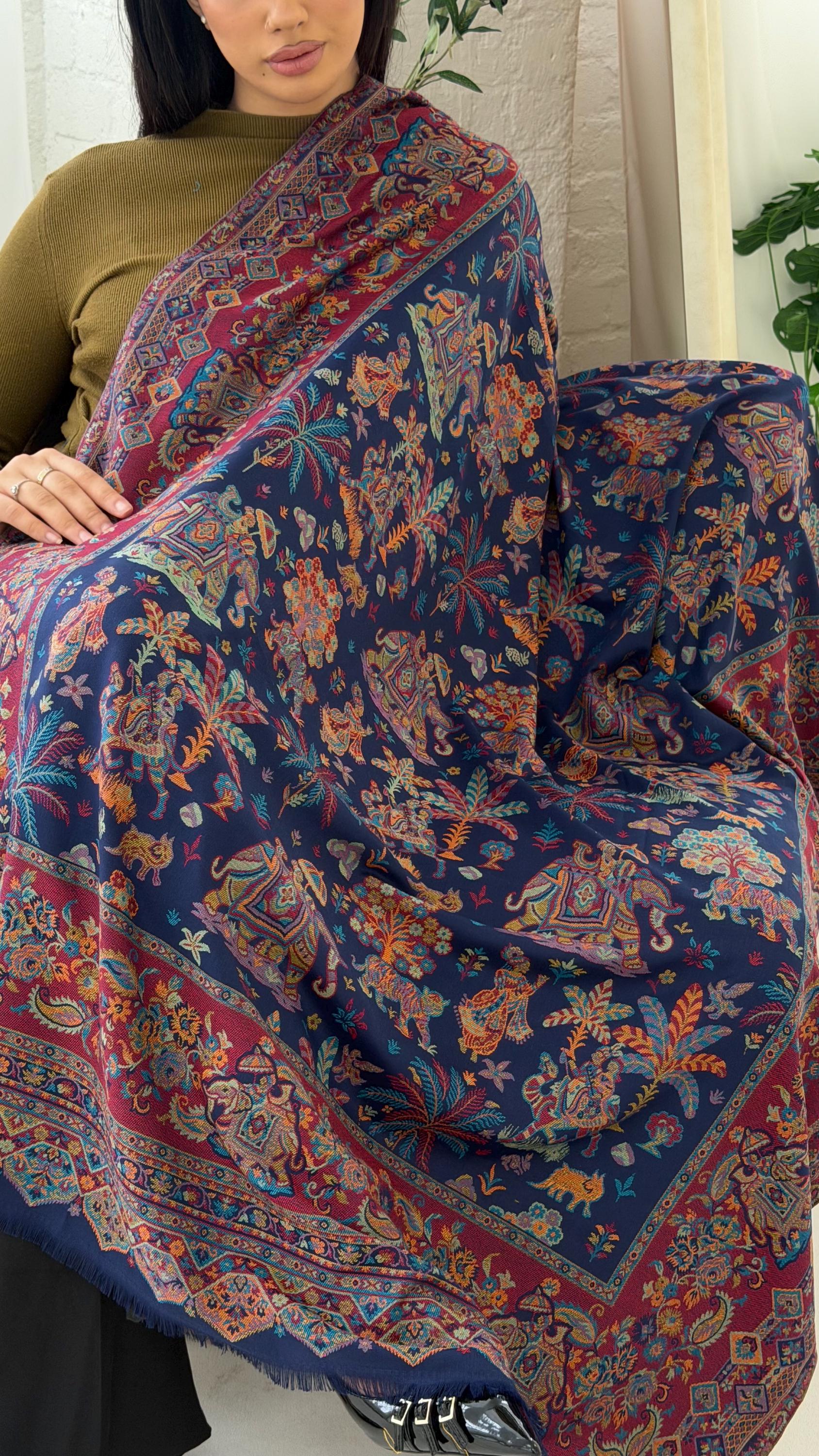 Woman holding a blue patterned pashmina shawl scarf, colorful patterned scarf with intricate designs.