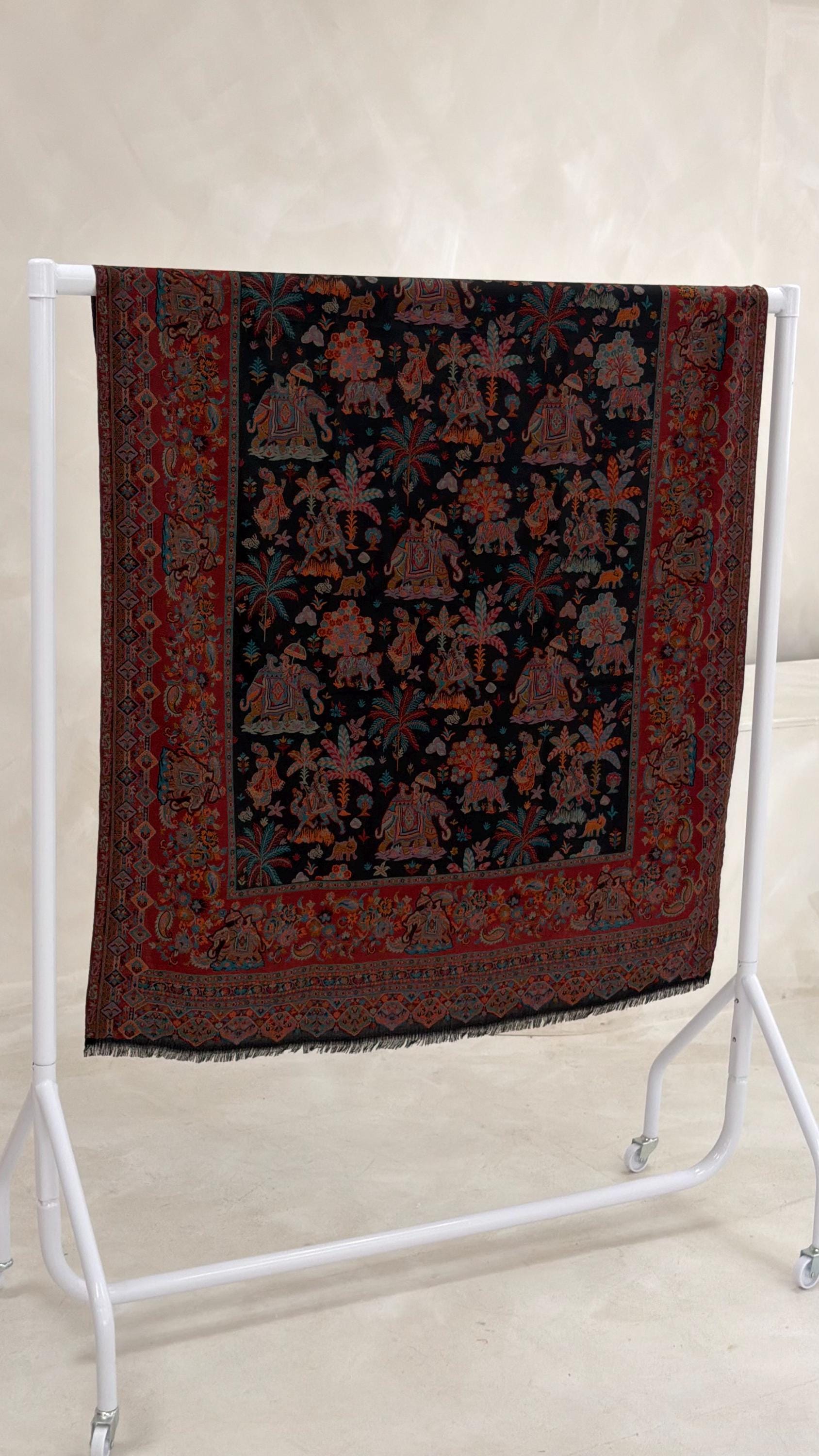 black patterned pashmina shawl scarf with intricate patterns on a white stand against a light background