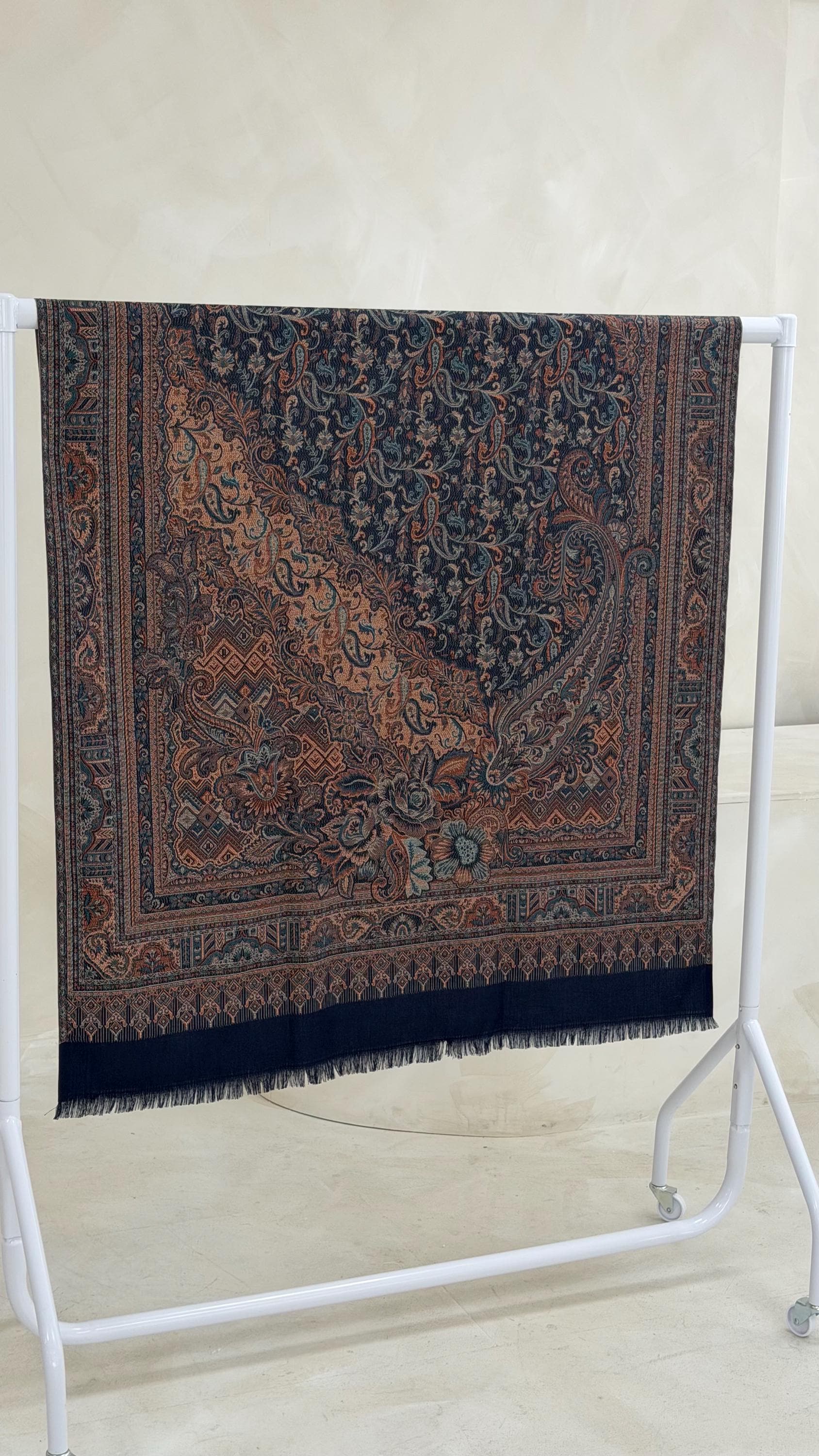 Blue scarf with intricate patterns on a white stand against a light background