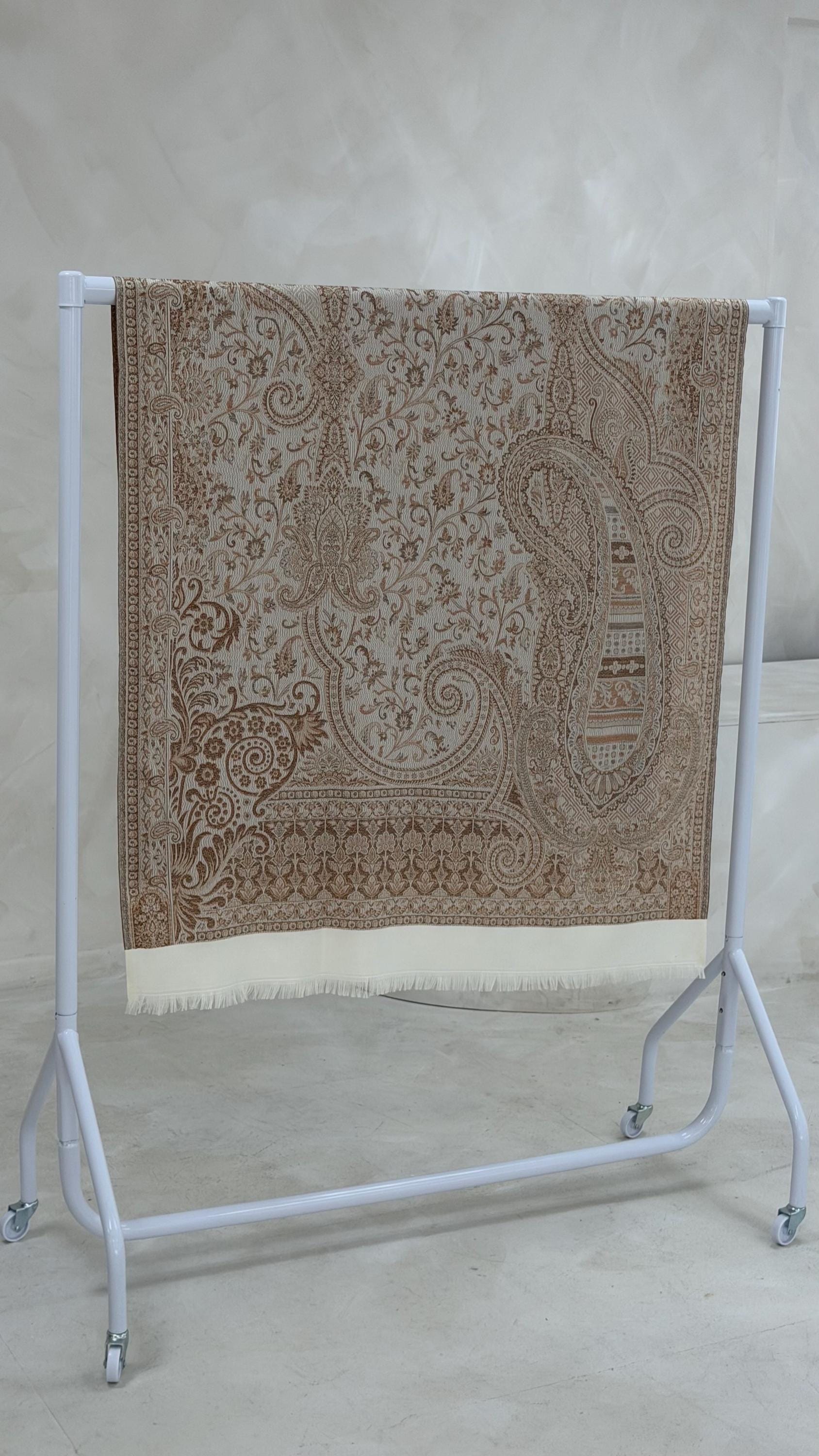 Patterned cream scarf on a white stand against a plain background