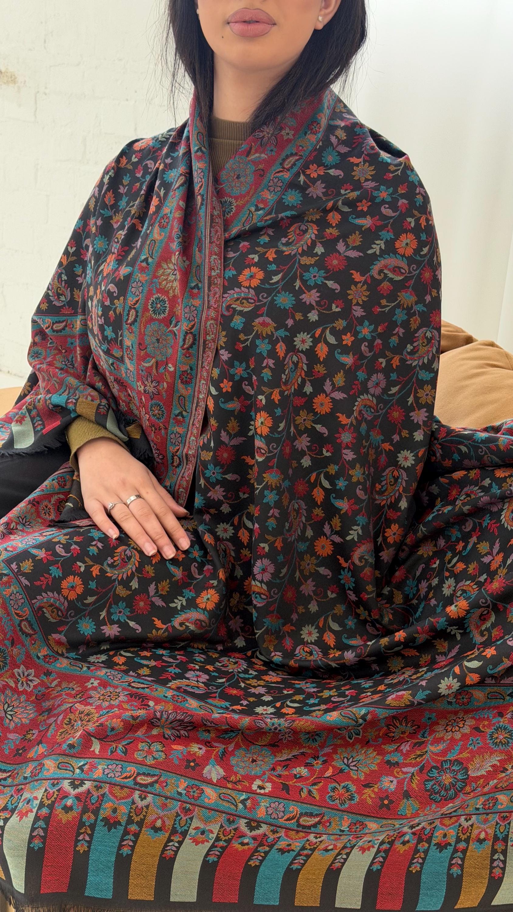 Person wearing a colorful patterned pashmina shawl sitting on a couch.