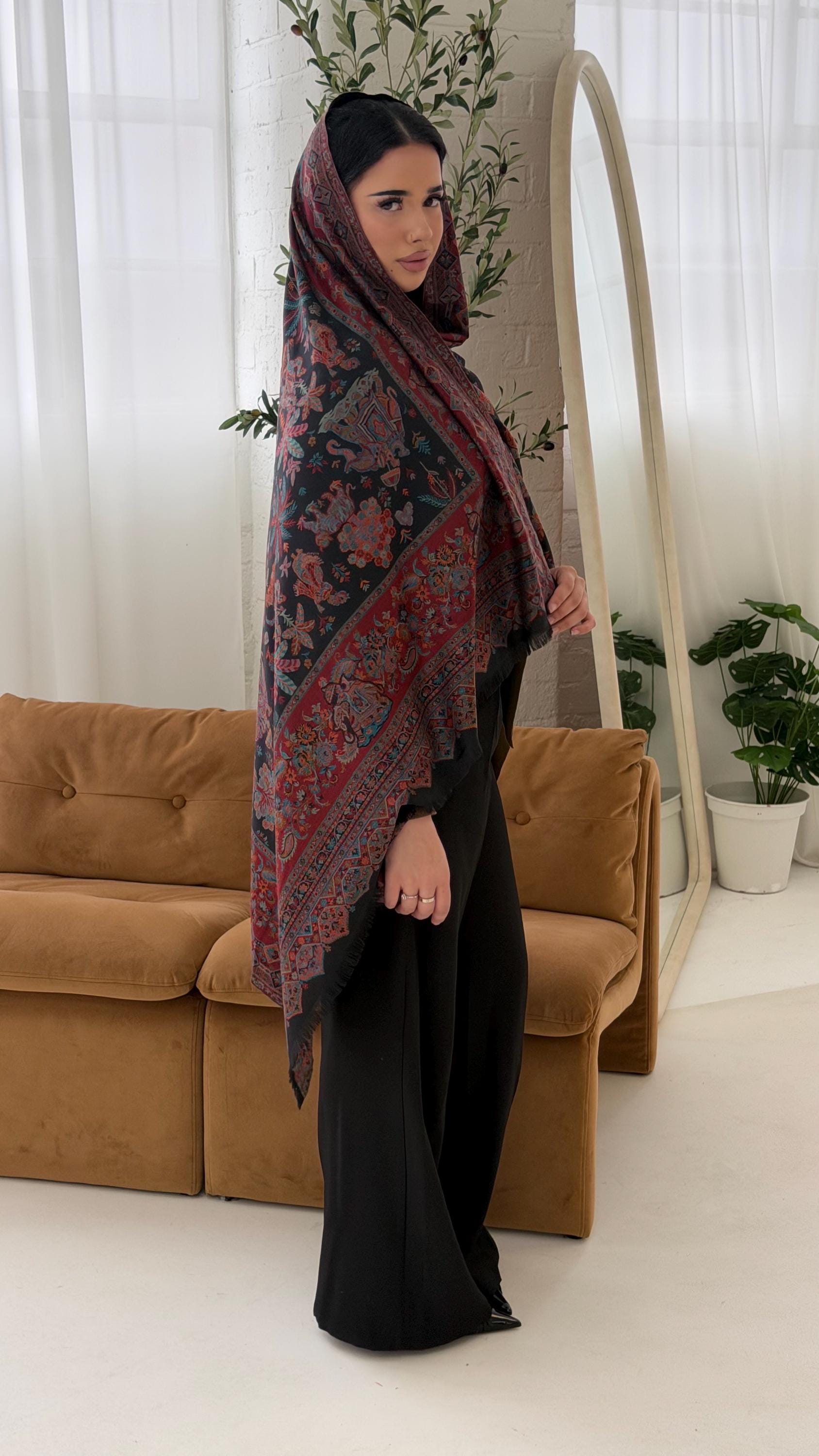 Woman wearing a black patterned pashmina shawl scarf in a living room setting